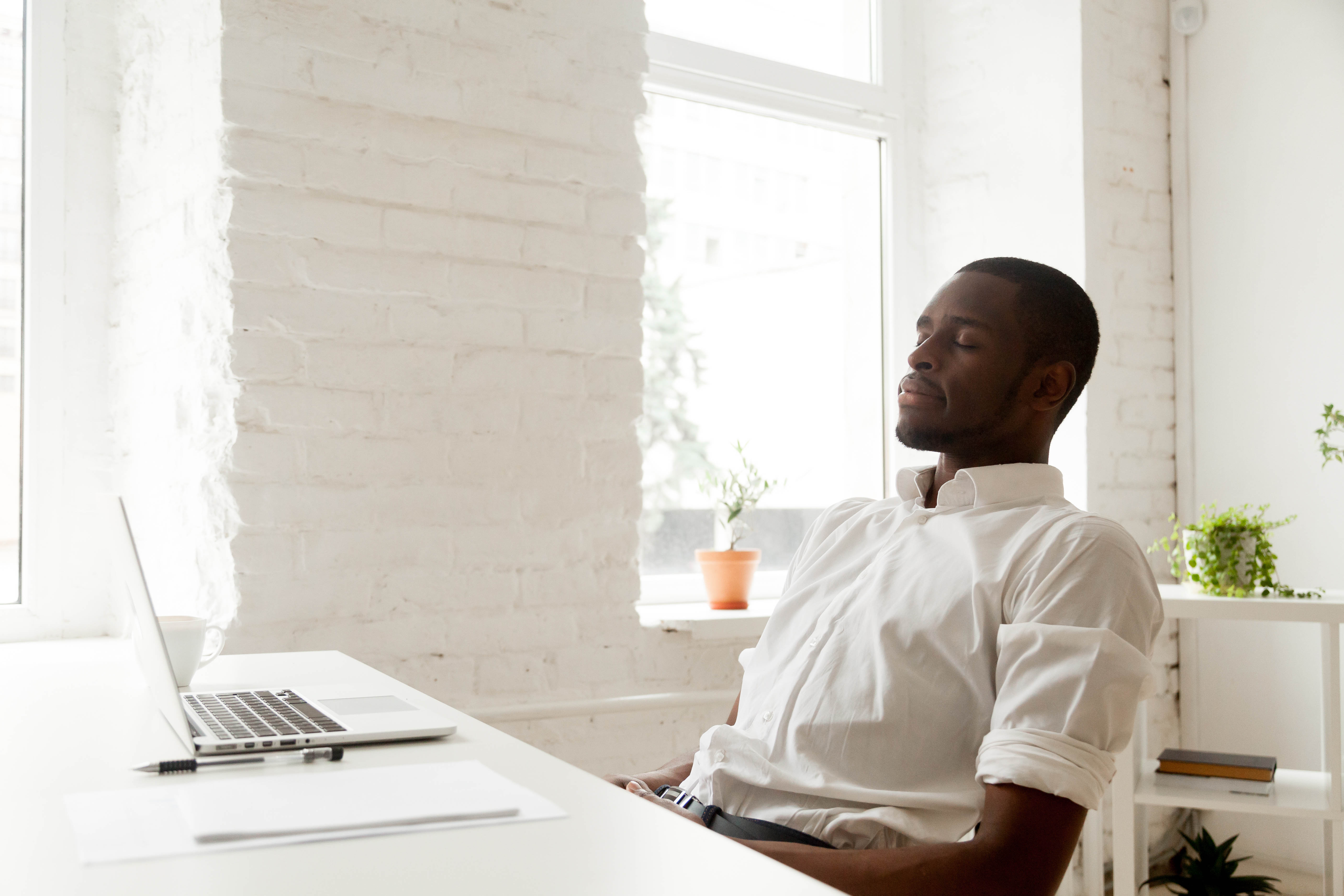 Middle aged man sitting at his desk, leaning back with his eyes closed Middle aged man sitting at his desk, leaning back with his eyes closed